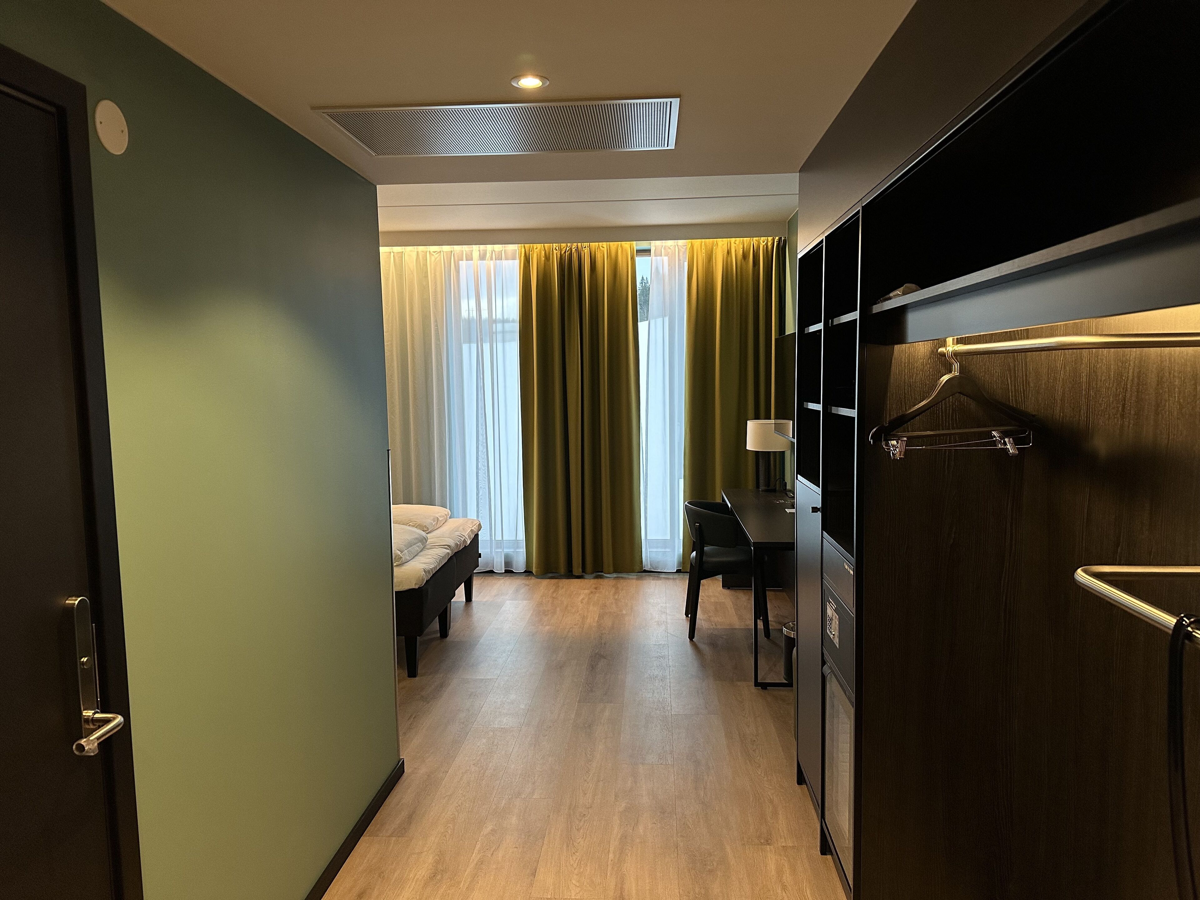 Una habitación de hotel con una cama, un escritorio y un armario.