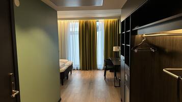 Una habitación de hotel con una cama, un escritorio y un armario.