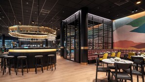 A modern restaurant interior with a bar area, high ceilings, and a colorful mural. - Thon Hotel Snø (Lorenskog)