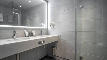 Un bagno moderno con uno specchio grande, un lavandino, una doccia e un cestino.