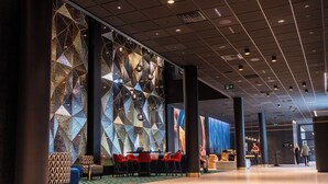 A modern hotel lobby with geometric wall patterns, red and patterned seating, and a reception area. - Thon Hotel Snø (Lorenskog)