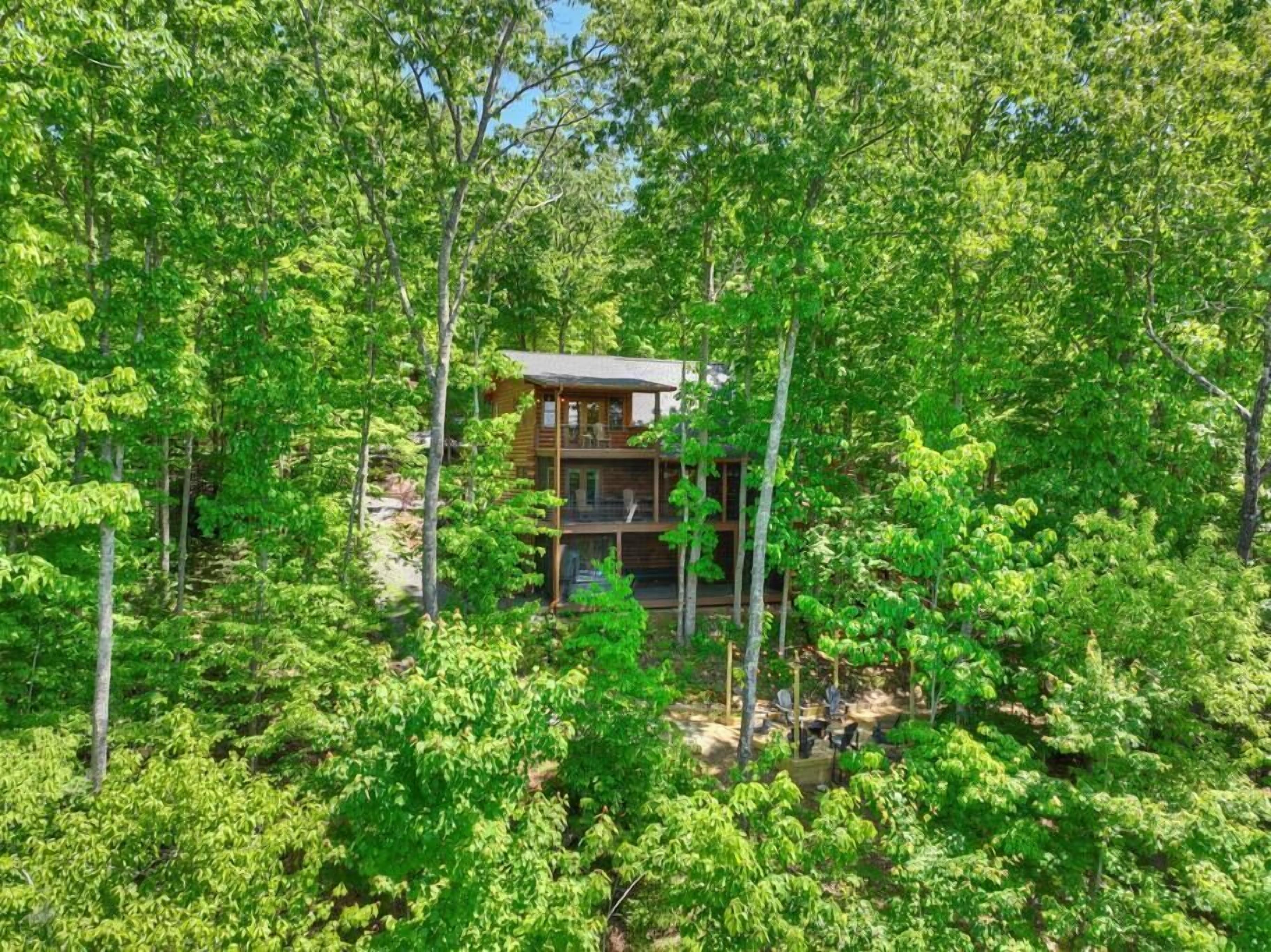 Eine zweistöckige Blockhütte, umgeben von dichtem Wald.
