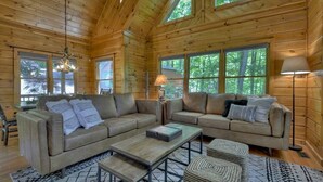 A log cabin interior with a large sofa set, a coffee table, and a lamp. - Cedar Ridge | Hot Tub + Game Room + Fire Pit (Blue Ridge)