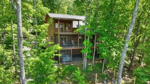 A two-story log cabin surrounded by dense forest. - Cedar Ridge | Hot Tub + Game Room + Fire Pit (Blue Ridge)