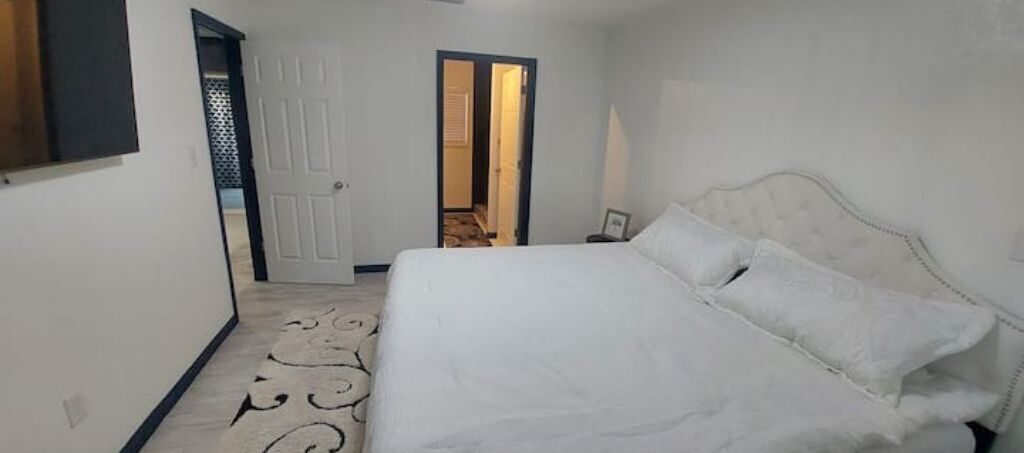 Un dormitorio con una cama grande, una puerta que da a otra habitación y una alfombra estampada.