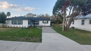 A single-story house with a front yard, a driveway, and a tree.