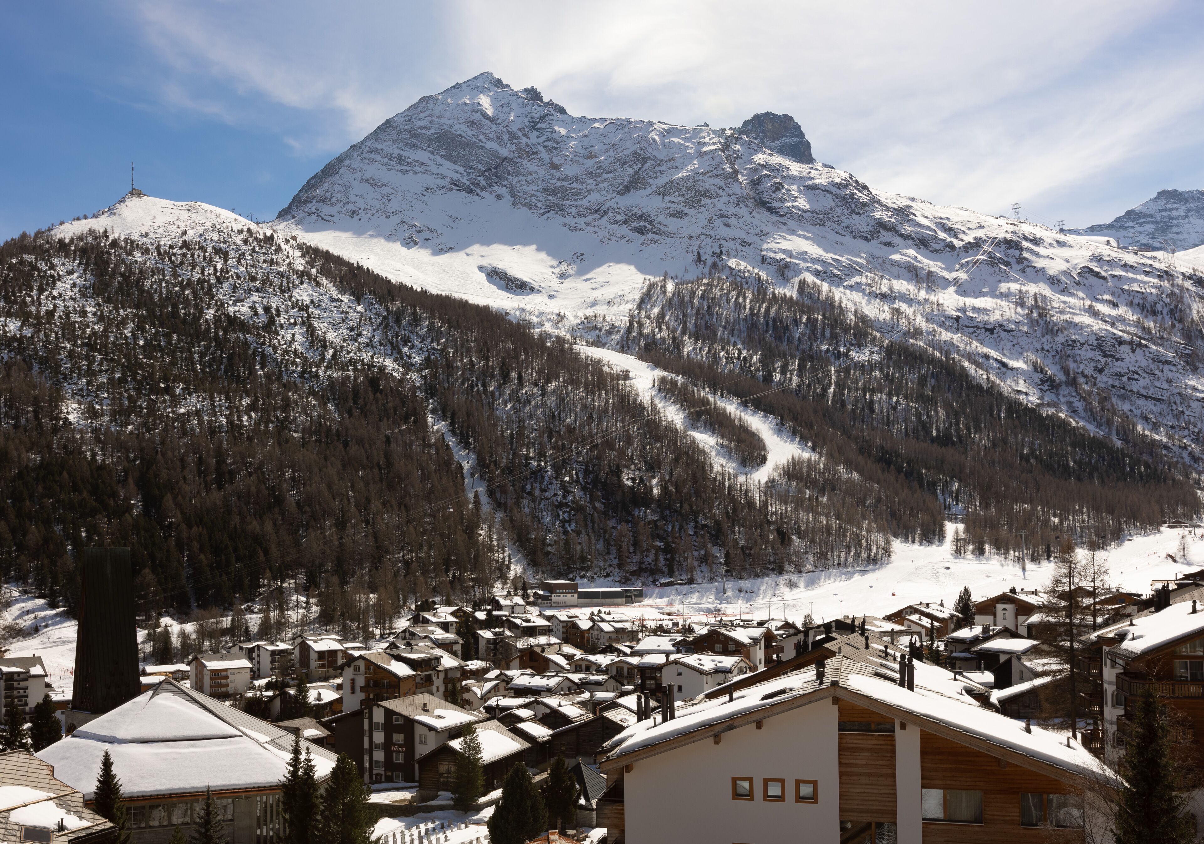 A snow-covered mountain town with buildings and a ski slope.