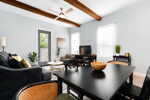 Una sala de estar moderna con un sofá oscuro, una mesa de comedor y un televisor.