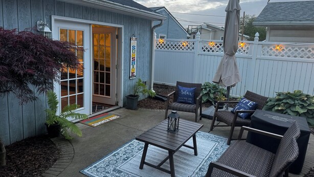 Une terrasse avec des meubles d’extérieur, une clôture en bois et un panneau indiquant « SOLEIL ».