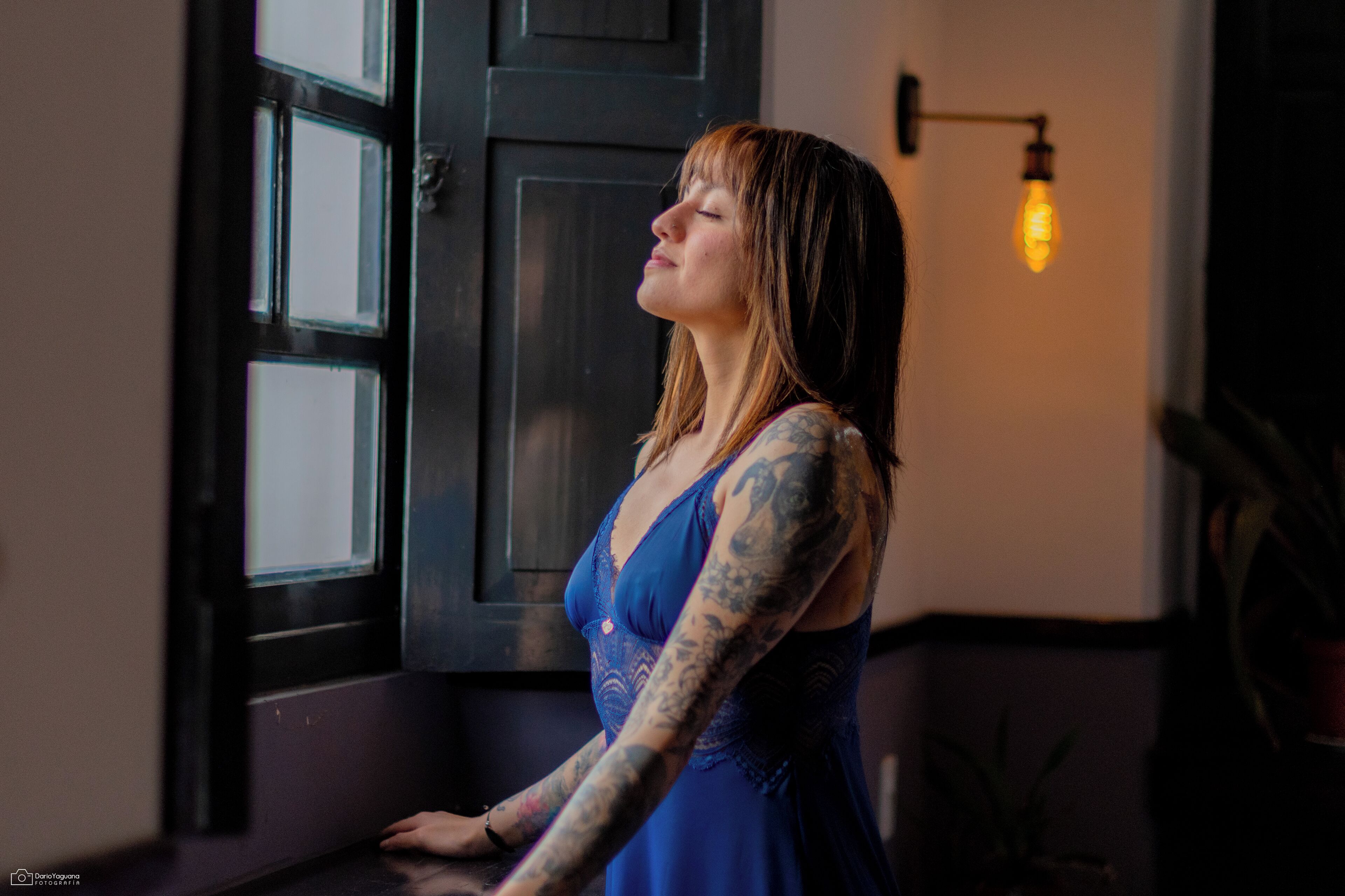 A person standing by a window with a light fixture above it.