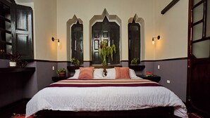 A large bed with a white bedspread and multiple pillows, flanked by two nightstands with small potted plants. - La Banksia Hotel (Quito)