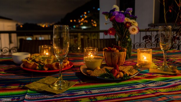 A dining table set with plates of food, glasses, and candles, with a view of the city at night. - La Banksia Hotel (Quito)