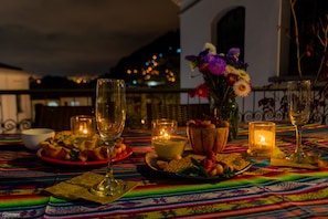 A dining table set with plates of food, glasses, and candles, with a view of the city at night. - La Banksia Hotel (Quito)