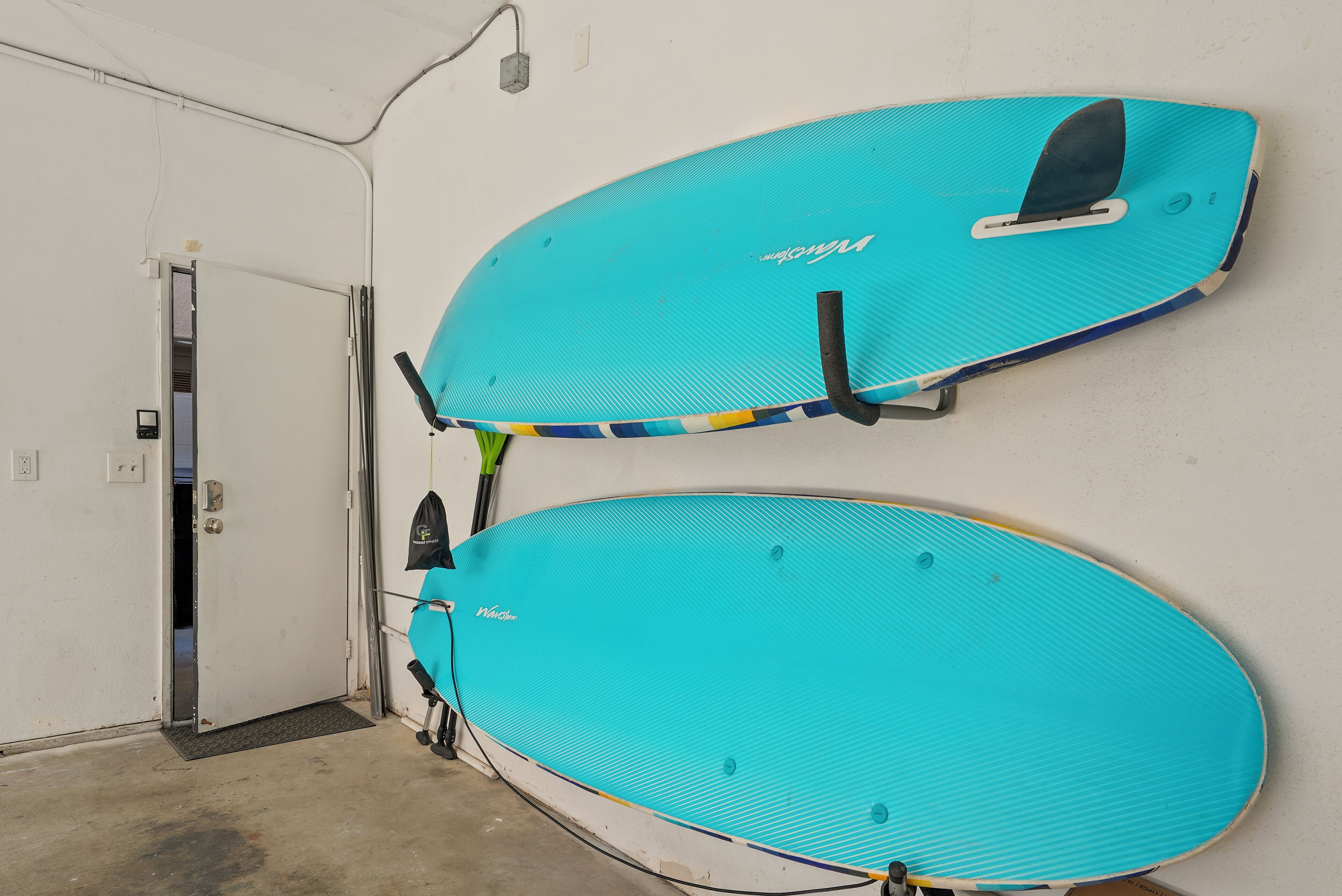Twee surfplanken hangen aan een muur in een kamer met een deur en een klein opstapje naar de vloer.