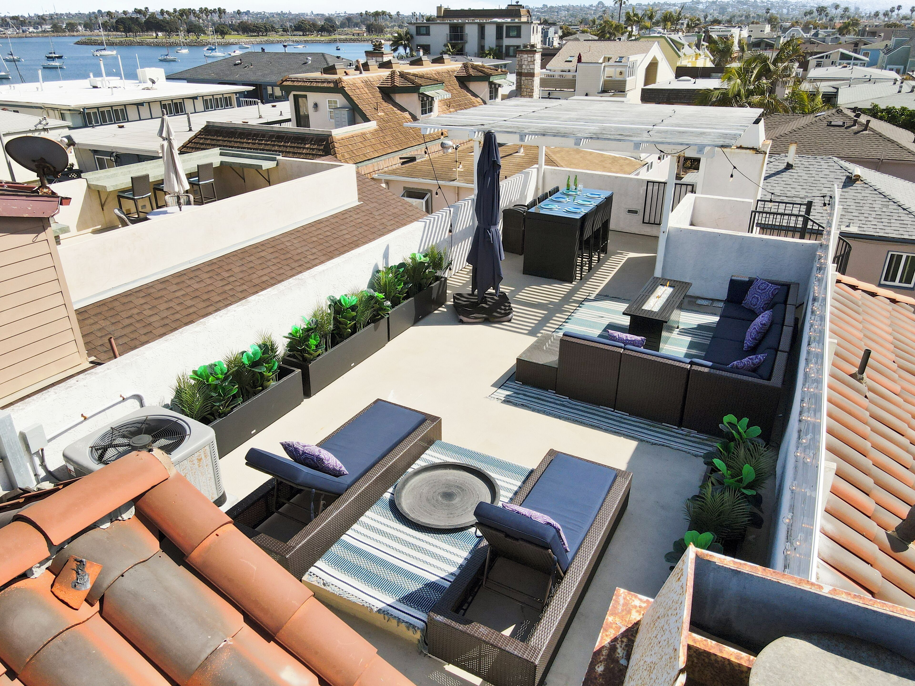 A rooftop terrace with outdoor furniture, a fan, and potted plants.