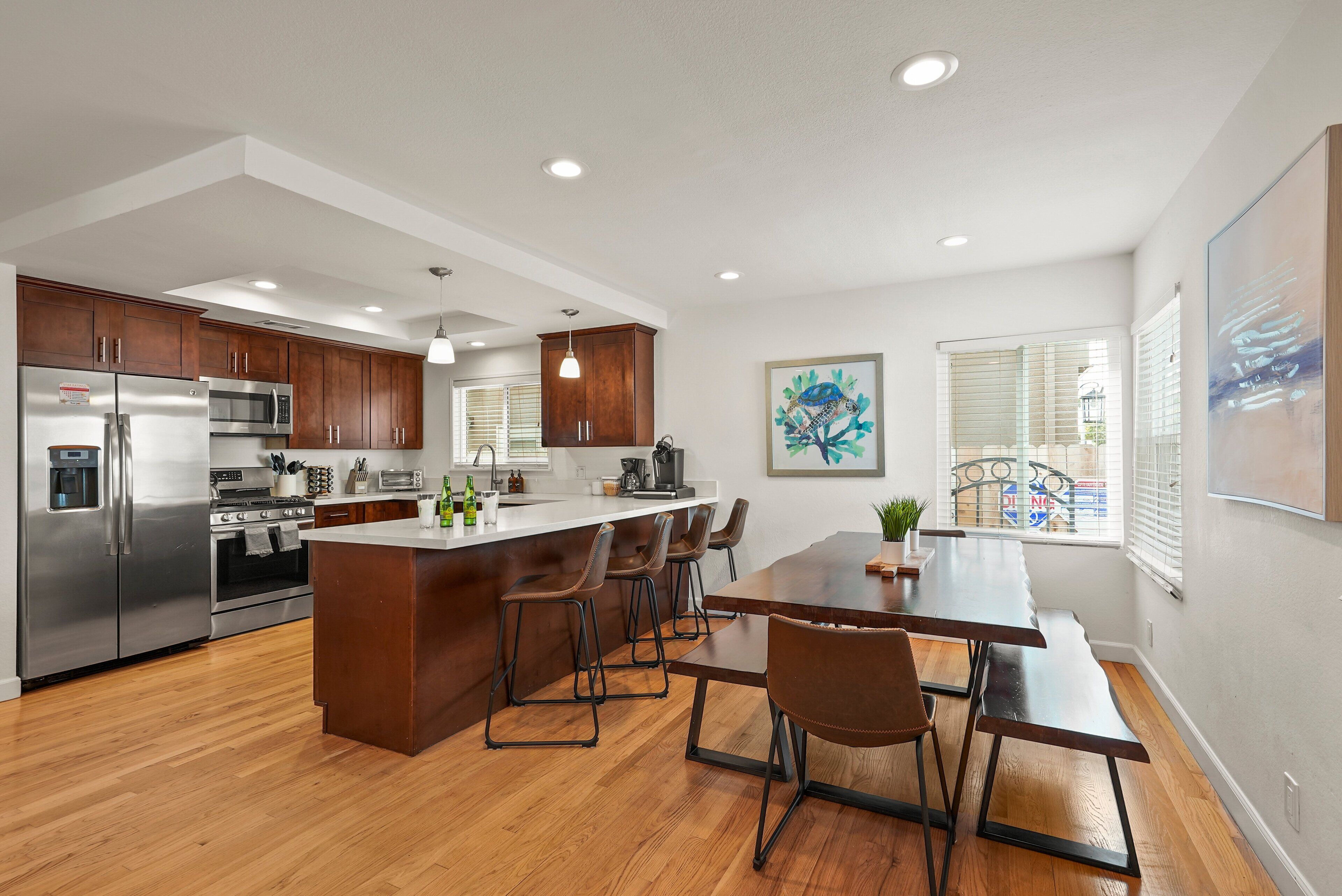 Una cocina moderna con electrodomésticos de acero inoxidable, armarios de madera y una isla central con taburetes de bar.