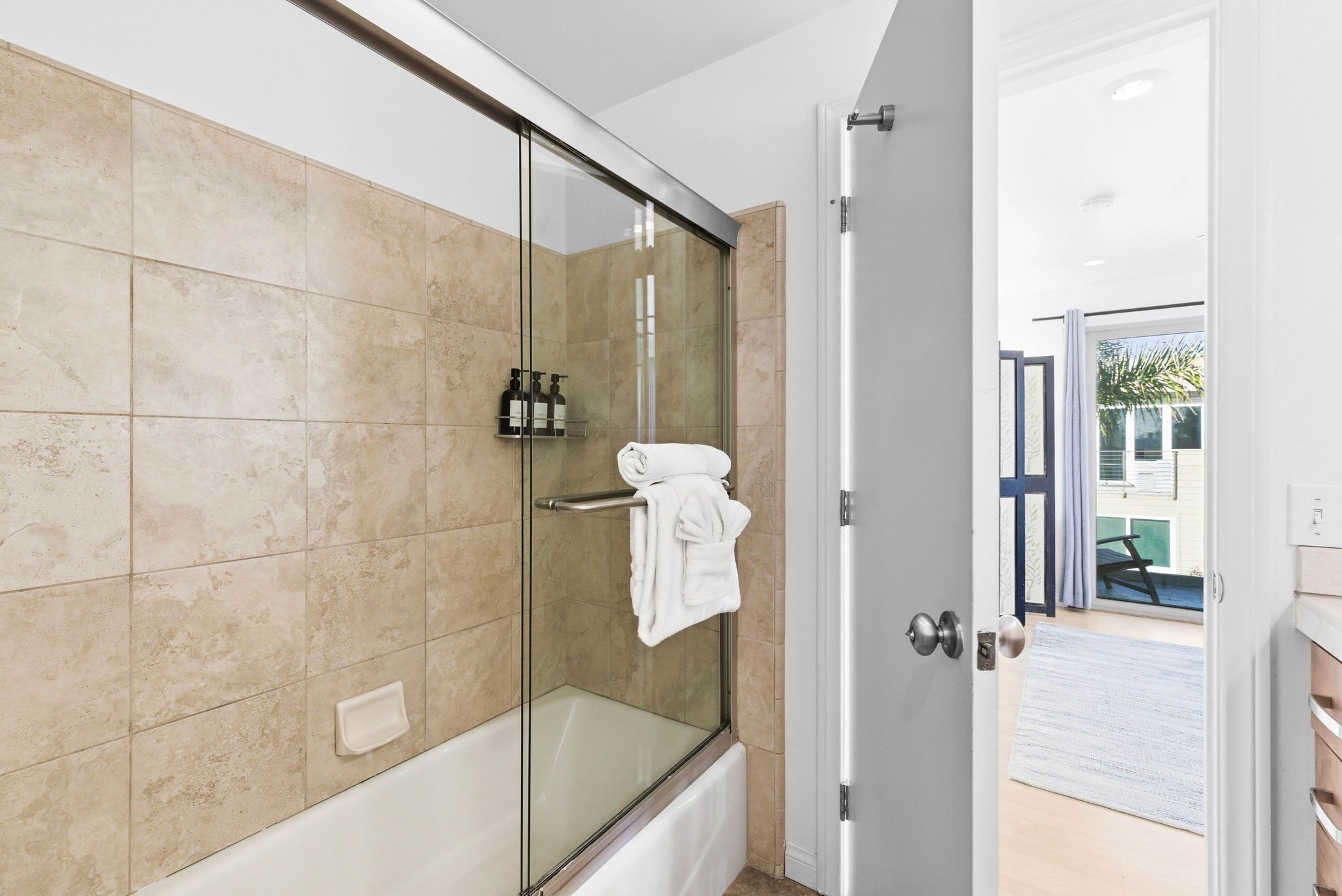 A modern bathroom with a glass-enclosed shower, beige tiles, and a towel rack.