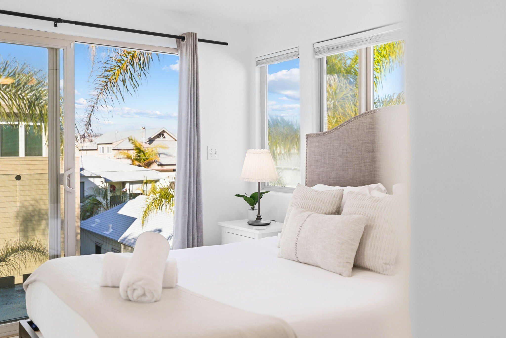 A modern hotel room with a large bed, a bedside table with a lamp, and a view of the outside.