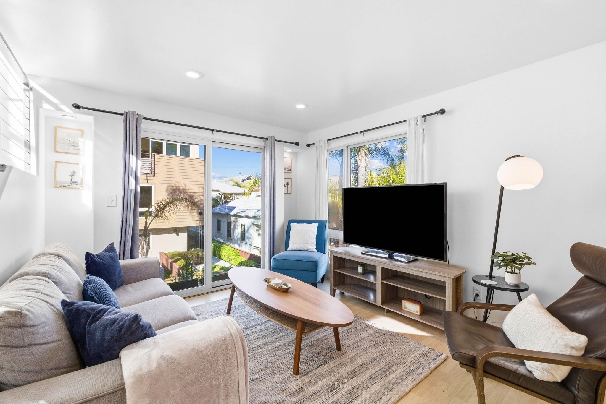 Una sala de estar moderna con sofá, sillón, mesa de centro, televisor y vistas al exterior.