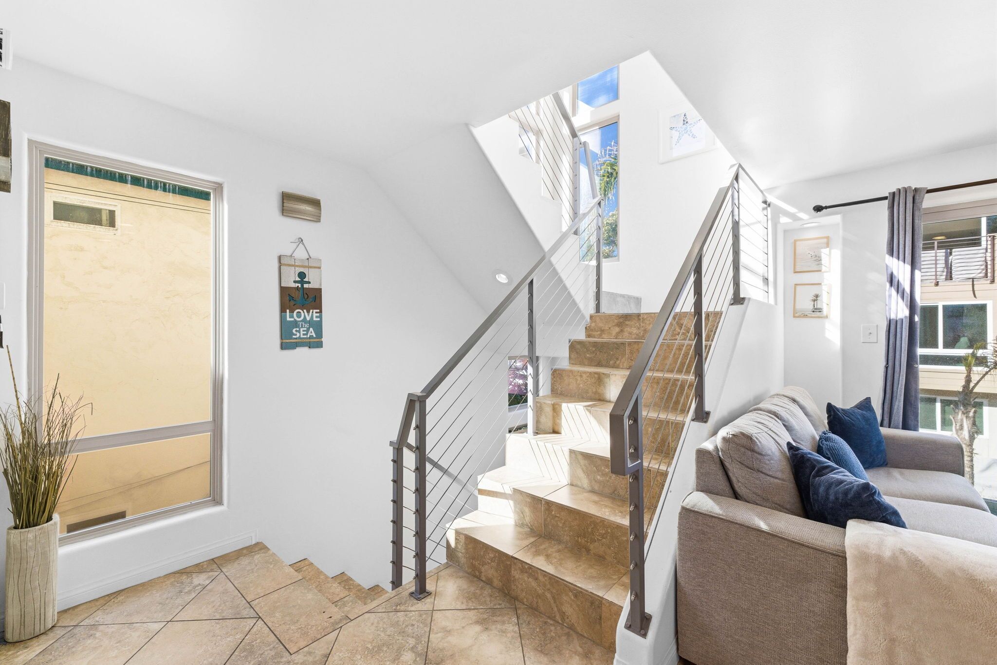 Een modern interieur met een trap, een bank en een raam met uitzicht.