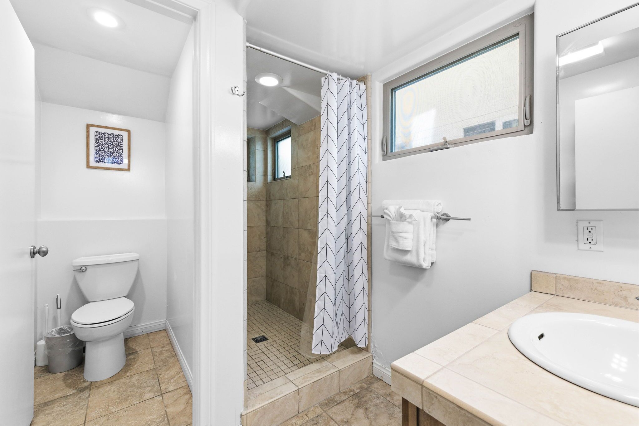 A bathroom with a toilet, shower, and sink.