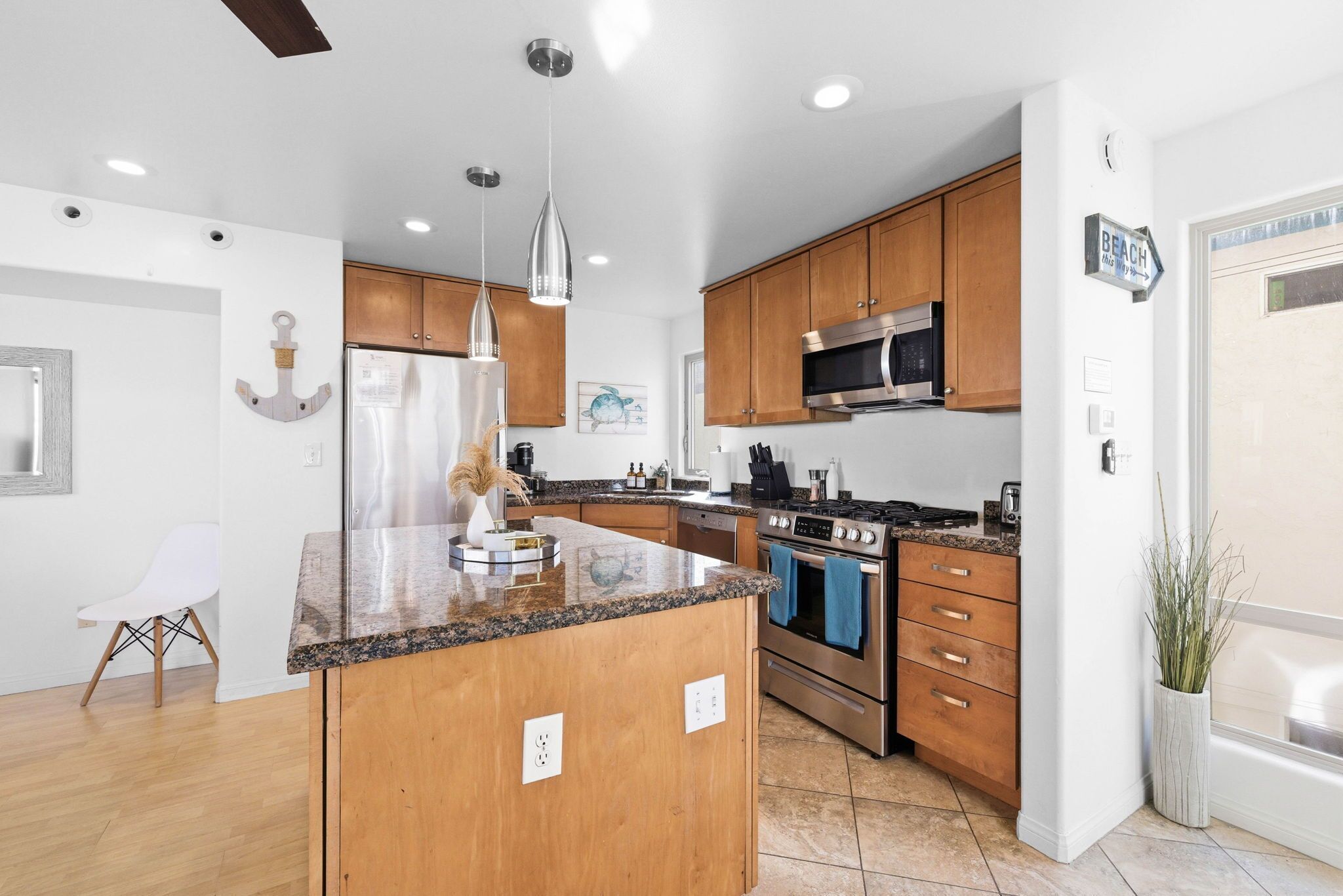 A modern kitchen with wooden cabinets, stainless steel appliances, and a granite countertop island.