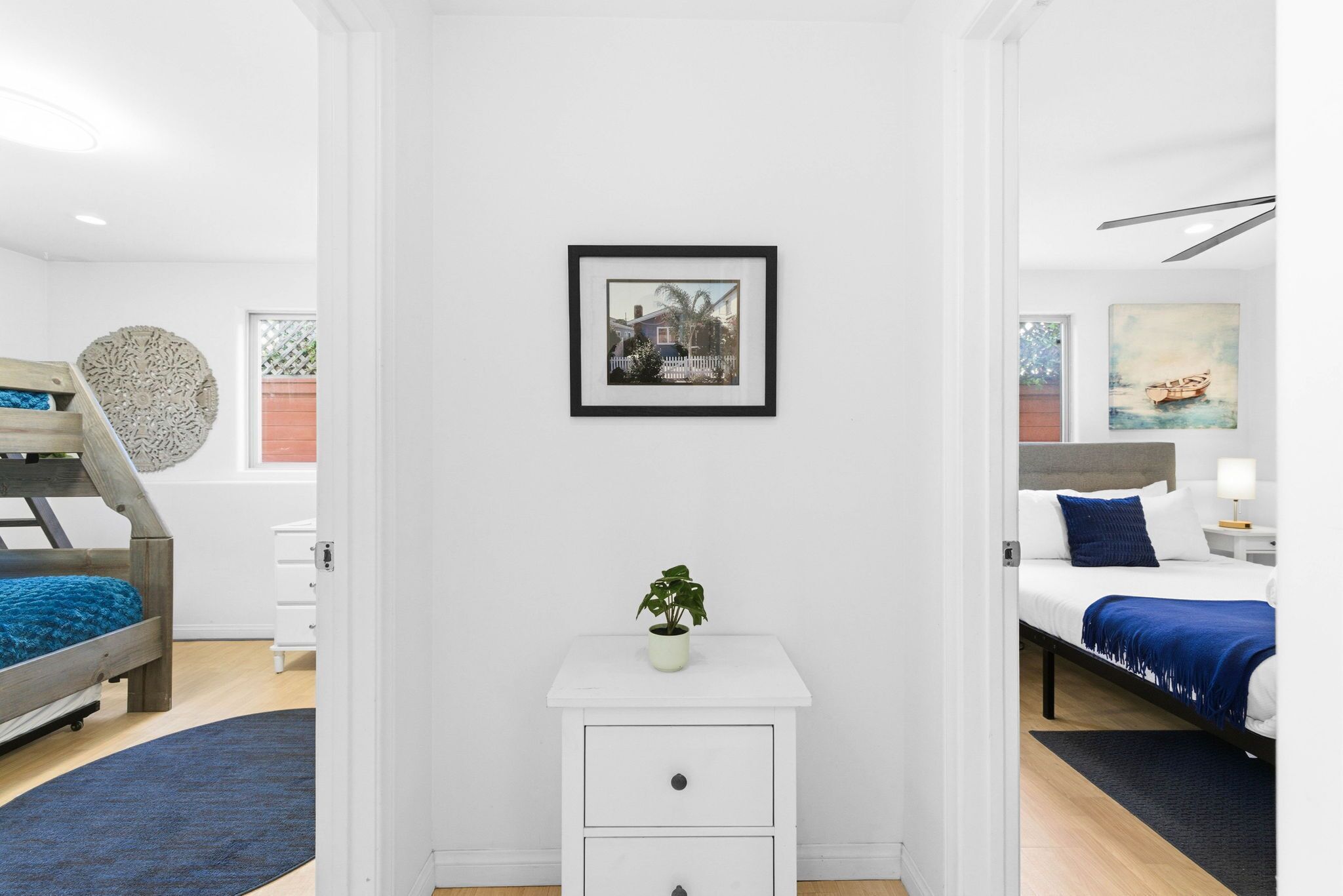 A modern bedroom with a bunk bed, a bedside table with a plant, and a framed picture on the wall.
