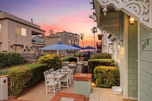 A patio with a grill, outdoor seating, and umbrellas.