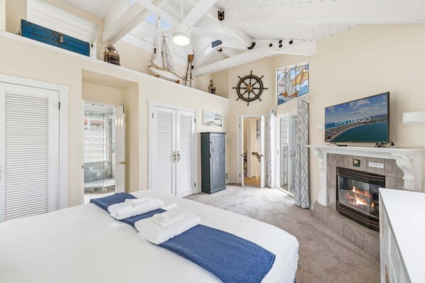 A hotel room with a bed, a fireplace, a TV, and a view of San Diego.