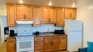 Una cocina compacta con armarios de madera, una estufa blanca, un fregadero y un refrigerador.