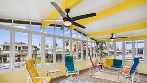A covered outdoor area with multiple chairs and a ceiling fan. - All Day Bay Dream by Ryson Vacation Rentals (Galveston)