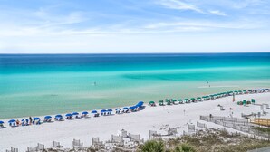 Una playa con hileras de sombrillas azules y arena blanca.