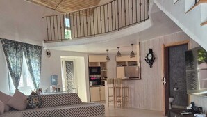 A spacious living area with a large sofa, a blue ottoman, and a kitchen in the background. - Villa Bord de mer Avec Piscine Privée (Saly)