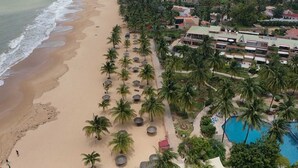 An aerial view of a beach resort with palm trees, a swimming pool, and beachfront properties. - Villa Bord de mer Avec Piscine Privée (Saly)