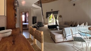 A spacious living area with a wooden dining table, a sofa set, and a staircase leading to an upper level. - Villa Bord de mer Avec Piscine Privée (Saly)