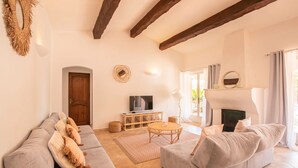 A living room with a sofa set, a television, a fireplace, and a dining area.