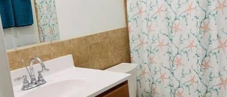 A bathroom with a white sink, a toilet, and a shower curtain with a floral pattern.