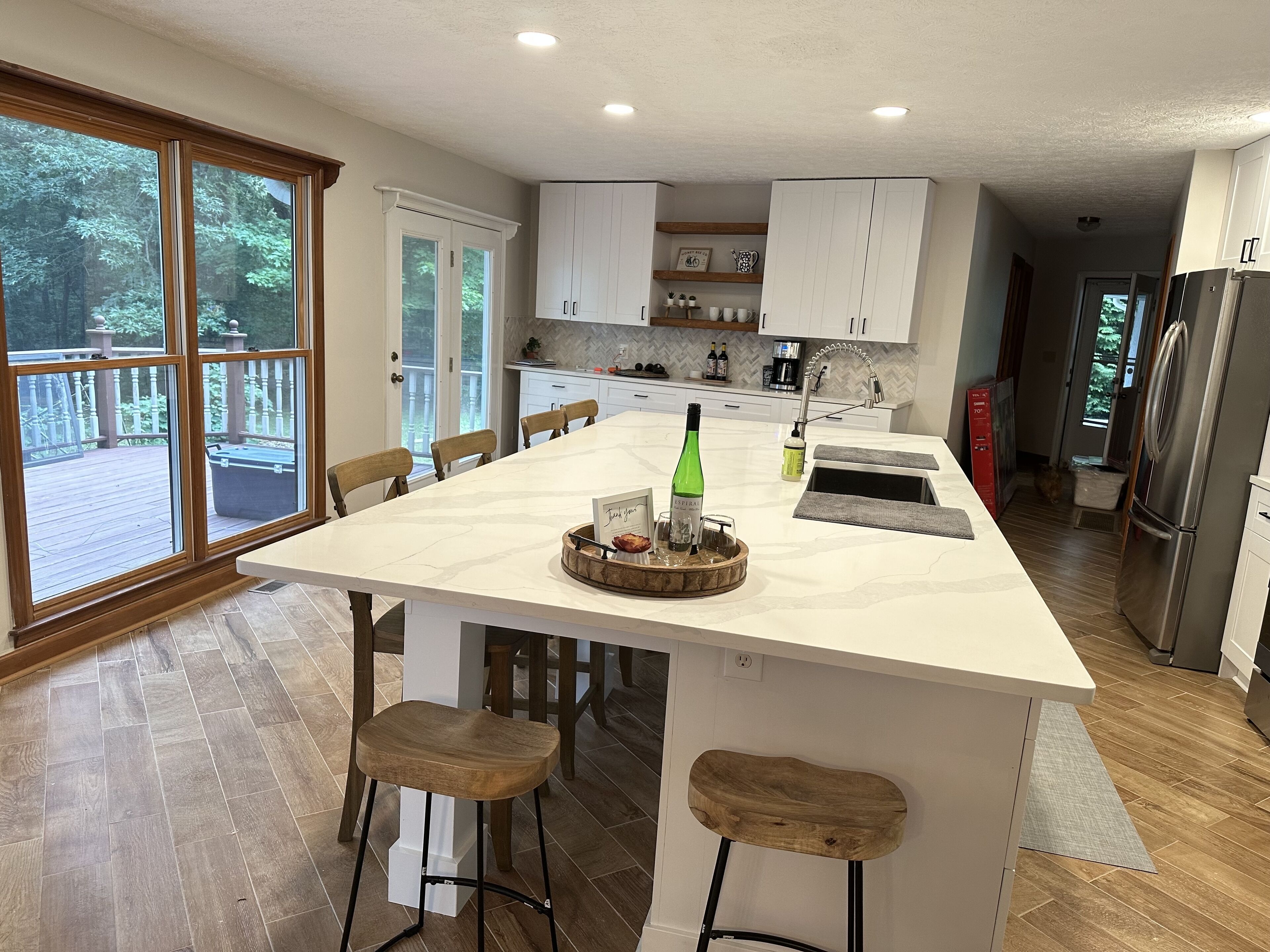 A spacious kitchen with a large island, wooden chairs, and a view of a deck.
