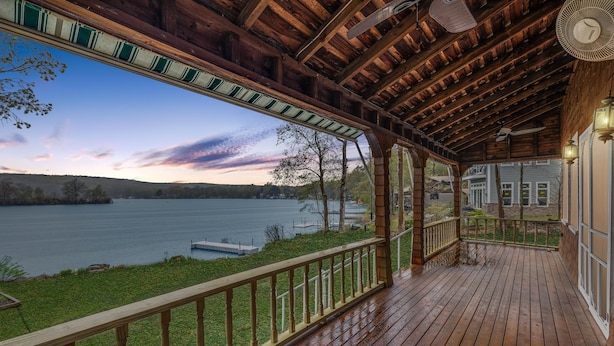 Un muelle de madera con vista a un lago y una casa al fondo.