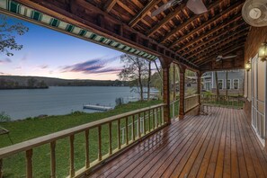 Une terrasse en bois offrant une vue sur un lac et une maison en arrière-plan.