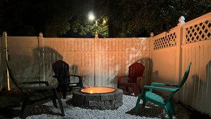 An outdoor seating area with a stone fire pit surrounded by white pebbles, three chairs, and a wooden fence. - Beautiful Villa in Myrtle Beach within 4 min walk to the beach (Myrtle Beach)