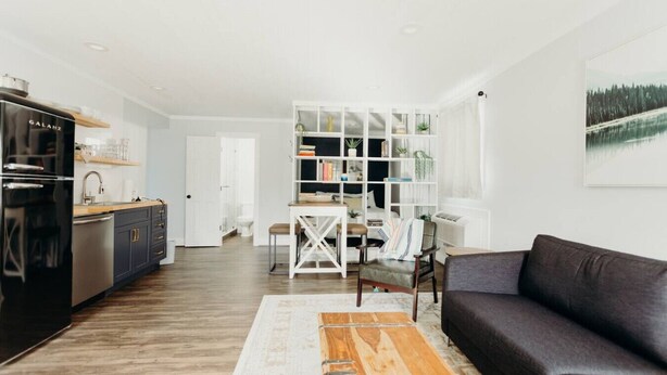 A modern living room with a dark sofa, wooden coffee table, and a white bookshelf.