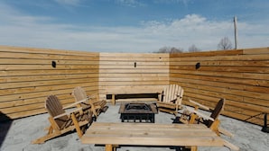 An outdoor wooden deck with a central fire pit and seating area.
