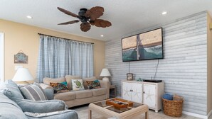 Un salon avec un canapé, une table basse et un ventilateur de plafond.