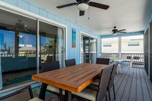 A covered outdoor area with a wooden table and chairs, glass sliding doors, and ceiling fans. - Heated Pool, 3- 5 minute walk to beach, restaurants. Pet Friendly. (Fort Myers Beach)