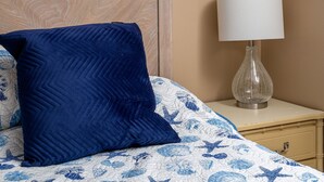 Une chambre à coucher comprenant un lit, une table de chevet, une lampe, un rideau et des éléments décoratifs sur les murs.