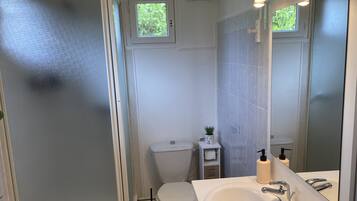 A modern bathroom with a white toilet, a sink with a mirror, and a small window above the toilet.