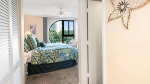 Un dormitorio con cama, ventilador de techo, decoración de estrella de mar y vistas al exterior.