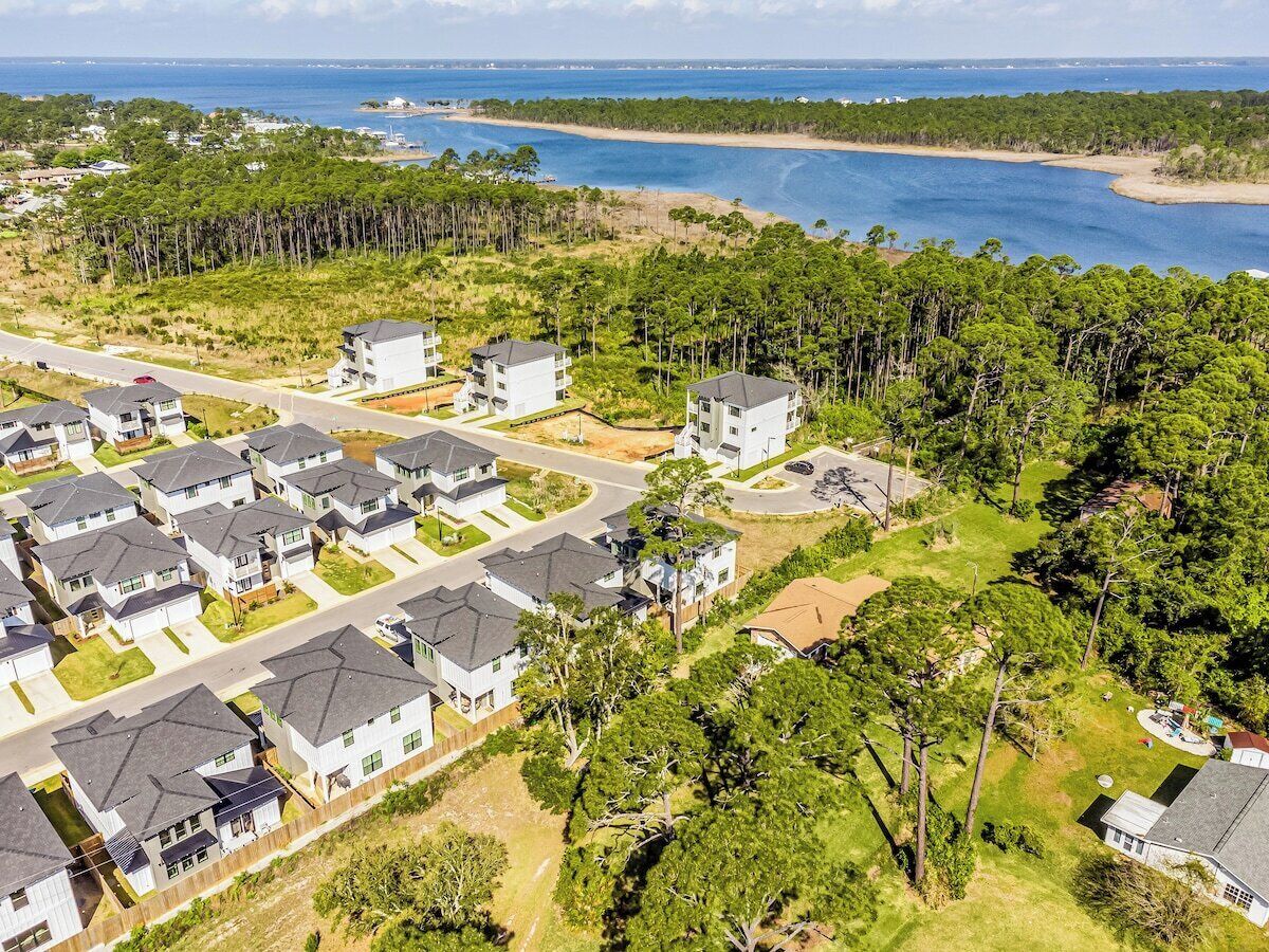 Un quartiere residenziale con diverse case a due piani, una strada e una spiaggia sullo sfondo.