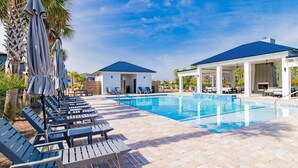 A pool area with lounge chairs, umbrellas, and a covered seating area.